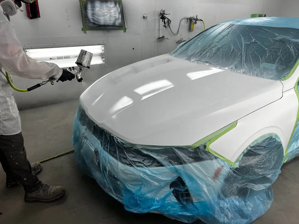 A car masked and taped in the booth with fresh color on the panels