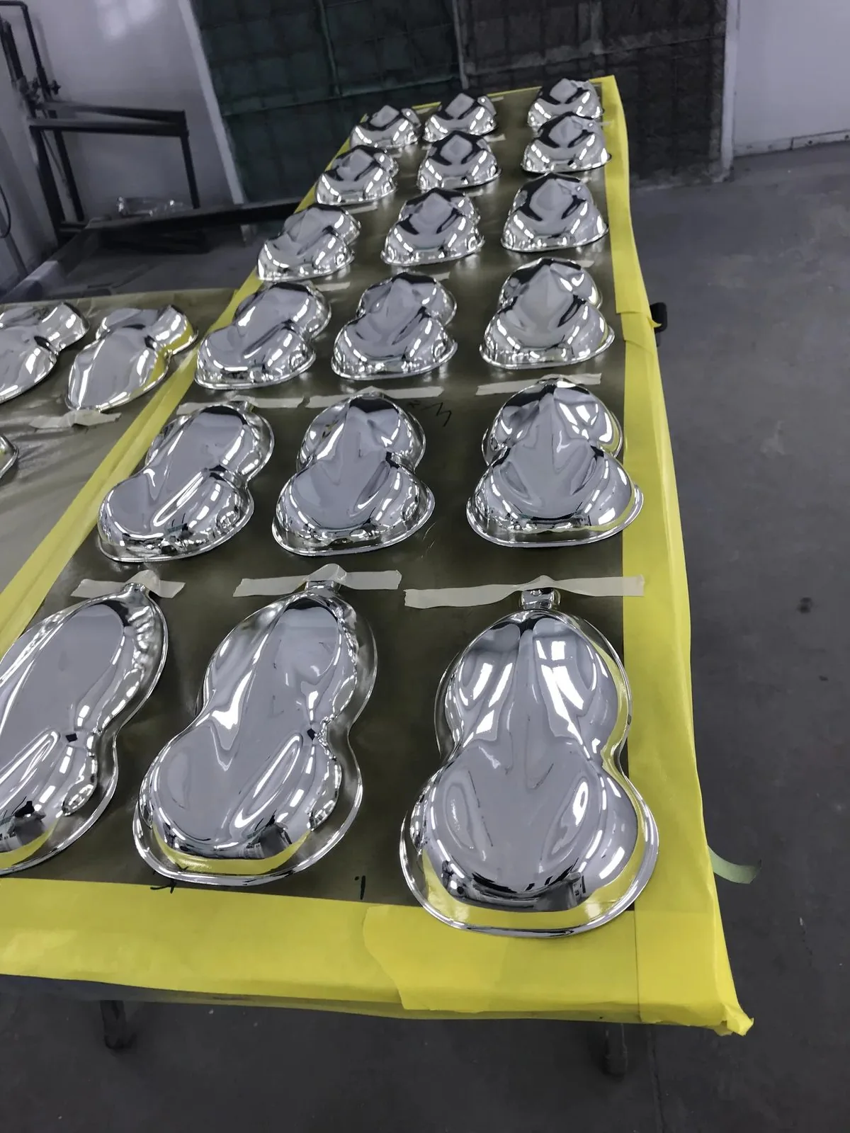 Rows of parts finished in mirror chrome on a masked bench