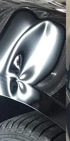 Hail dents picked out on a black panel