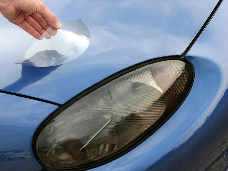 A hand laying a precut clear Lamin-x film over a headlight (photo: Lamin-x)